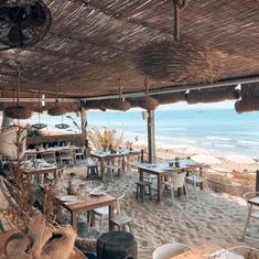 an outdoor dining area on the beach with tables and chairs set up for people to eat