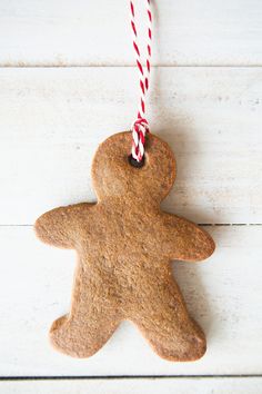 a gingerbread man ornament hanging from a red and white striped string on a white wooden surface