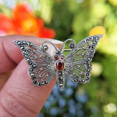 Metal: Solid Sterling Silver Gemstone: Marcasite + Red Glass Body/Eyes Size: 3.7cm x 2.1cm Weight: 5.3 grams  Hallmarked: No (under 7.78 grams) A fabulous solid sterling silver butterfly brooch that's been studded with sparkling marcasite stones and a garnet coloured glass body and eyes.  The brooch is a good size and secured using a pin and catch at the rear. *RETURNS* We accept returns within 30 days, provided the item has not been personalised. Return postage costs are the responsibility of t Collectible Silver Gemstone Brooches, Antique Silver Butterfly Jewelry, Silver Gemstone Brooch Collectible, Ornate Sterling Silver Brooches For Gifts, Silver Stamped 925 Brooches As Gifts, Sterling Silver Brooches Stamped 925 For Gift, Sterling Silver Brooch Stamped 925 For Gift, Sterling Silver Brooch Stamped 925 As Gift, Gift Sterling Silver Brooches Stamped 925