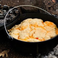 a skillet filled with food sitting on top of a fire pit next to coal