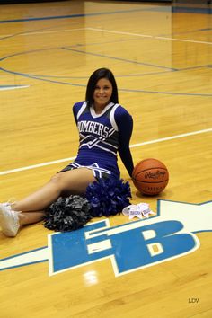 a woman sitting on the floor with a basketball in her hand and wearing a cheerleader outfit