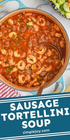 sausage tortellini soup in a blue pot on a white marble countertop with text overlay reading sausage tortellini soup