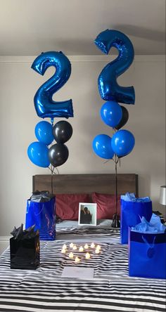 two balloons are in the shape of numbers on a bed with blue and black bags