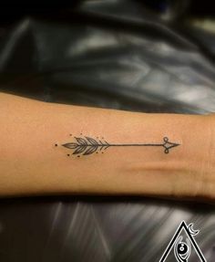 a woman's arm with an arrow tattoo on it