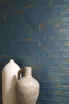 two vases sitting next to each other in front of a blue wall