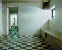 a person walking down a hallway with black and white checkered tile on the floor