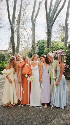 a group of women standing next to each other wearing dresses and holding bouquets in their hands