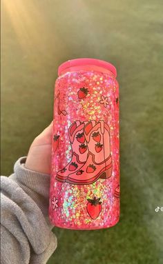 a person holding up a pink glittered cup with a cartoon character on the lid