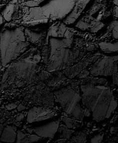 black and white photograph of the surface of an old rock wall with cracks in it