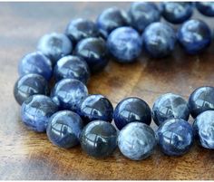 a close up of a necklace made out of blue marble beads on a wooden surface