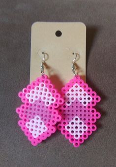 a pair of pink and white beaded earrings with hearts on them, hanging from a hanger