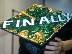 a person wearing a green and gold graduation cap with the word finn ally on it