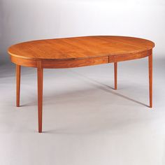 an oval wooden table with two drawers on one side and three leaves on the other