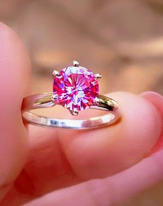 a person holding a pink diamond ring in their hand