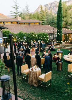 a group of people standing around a table in the middle of a yard with lights on it