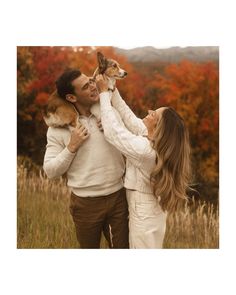 a man and woman holding two dogs in their arms