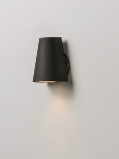 a black wall light mounted on the side of a white wall