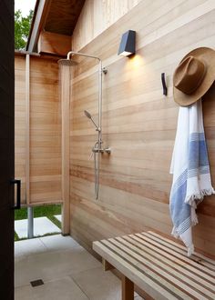 a hat and towel hanging on the side of a wooden wall next to a bench