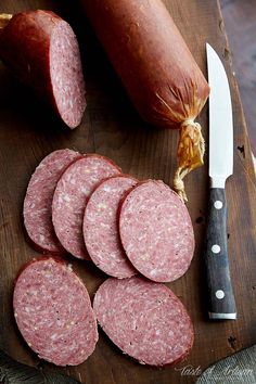 sliced sausages on a cutting board next to a knife