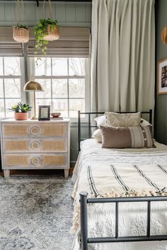 a bed room with a neatly made bed next to a night stand and two windows