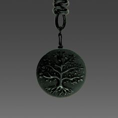 a black pendant with a tree on it