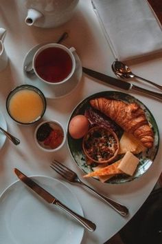 an assortment of breakfast foods and coffee on a white tablecloth with utensils