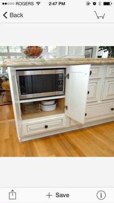 a kitchen with white cabinets and an oven in the center, on top of a wooden floor