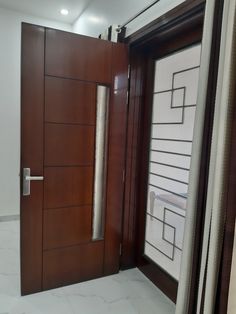 an open wooden door in a room with white tile flooring and large window coverings