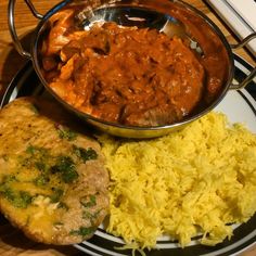 a plate topped with rice and meat covered in gravy next to a side dish