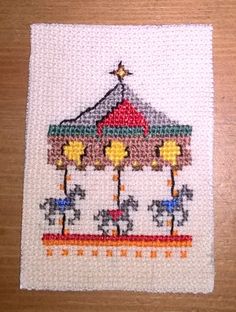 a cross stitch picture of a merry go round