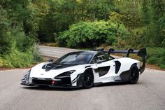 a white and black sports car parked on the side of a road next to trees