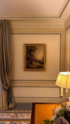 a living room with a painting on the wall next to a lamp and flowers in vases