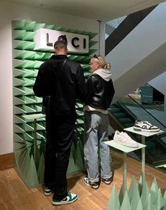 two people standing next to each other in front of a display case with shoes on it