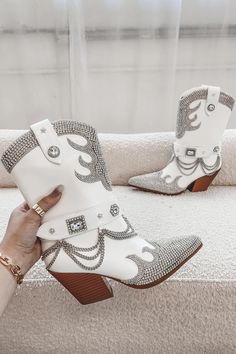 Made with white leather and adorned with crystal rhinestones and a silver chain, this statement boot is sure to turn heads. Heel height is 3.25" Sequin Tassel Dress, Wedding Guest Romper, Girl Boss Book, Party Bottoms, Western Shoes, Fringe Mini Dress, Western Booties, Amazing Lace, Native Style