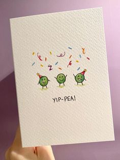 a hand holding up a card that says yip - peai with two green birds and confetti sprinkles