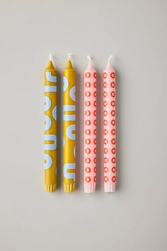 three yellow and pink toothbrushes sitting next to each other on a white surface