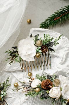 three wedding hair combs with flowers and pine cones on them, sitting next to evergreen branches