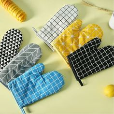 four oven mitts are lined up on a table with lemons and other kitchen accessories