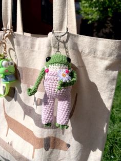 a crocheted frog keychain hanging from a tote bag