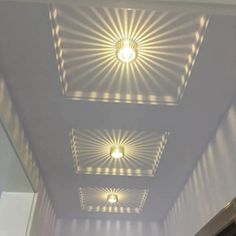 three ceiling lights that are on the side of a wall in a room with white walls