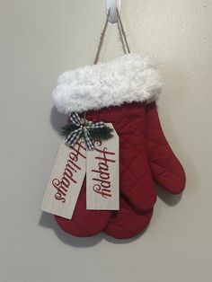 a pair of red mitts hanging on a wall with two tags that say happy home