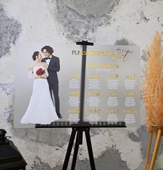 the wedding program is displayed on an easel next to a vase with dried flowers