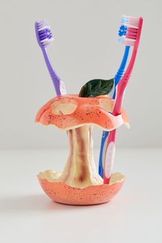 three toothbrushes sitting on top of each other in a mushroom like holder with leaves