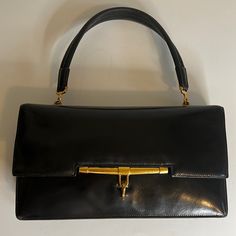 Hermes Palonnier Handbag In A Smooth Black Leather. Leather Shows Scratches And Corner Wear Consistent With Older Bag. Single Flat Top Handle With 5.5 Inch Drop. Creasing On Handle Leather. Dark Gold Tone Hardware With Tarnish. Front Top Flap With Hook Clasp Closure. Leather Lined Interior With Four Compartments - A Large Gusset Pocket, A Rear Slip Pocket Behind A Snap Closure Pouch And A Front Slip Pocket. Gold Embossed Hermes Paris Stamp. No Box Or Dust Bag. An Oldie But A Goodie In A Vintage Timeless Evening Shoulder Bag With Hasp Closure, Elegant Evening Satchel With Hasp Closure, Designer Satchel With Hasp Closure For Formal Occasions, Formal Rectangular Satchel With Magnetic Closure, Designer Formal Satchel With Hasp Closure, Designer Bags With Hasp Closure For Formal Occasions, Formal Handheld Bag With Palladium Hardware, Timeless Rectangular Evening Bag For Business, Modern Evening Satchel With Hasp Closure