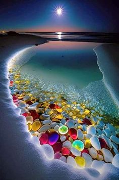 the beach is covered in many different colored rocks and pebbles, as well as a full moon