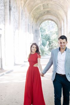 a man and woman holding hands while walking through an archway with arches in the background