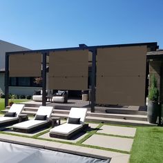 some white lounge chairs sitting on top of a grass covered field next to a swimming pool