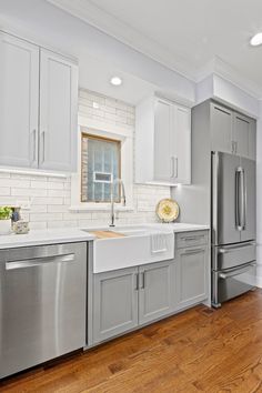 a large kitchen with stainless steel appliances and white counter tops, along with hardwood flooring