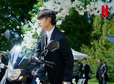 a man in a suit and tie standing next to a motorcycle with flowers on it