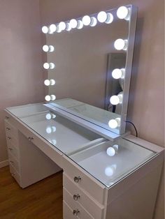 a white vanity with lighted mirror and drawers